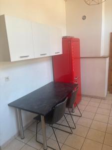 a kitchen with a black table and a red refrigerator at Belle appartement in Saint-Mihiel