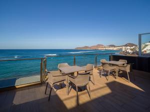 a deck with tables and chairs and the ocean at Sercotel Playa Canteras in Las Palmas de Gran Canaria