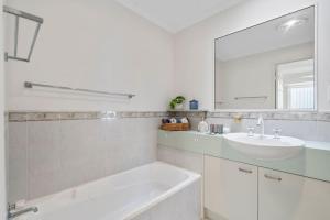 a white bathroom with a sink and a mirror at Cozy 2BR villa in Maroochydore in Maroochydore +14 photos
