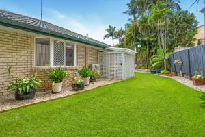 a backyard of a house with green grass and plants at Cozy 2BR villa in Maroochydore in Maroochydore