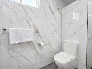 a bathroom with a white toilet and marble walls at Gladstone CBD Motel in Gladstone +26 photos