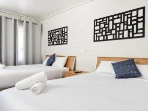 two beds in a room with white walls at Gladstone CBD Motel in Gladstone