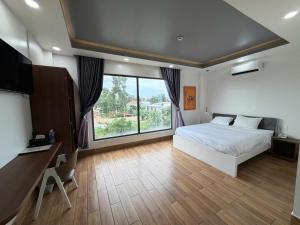a bedroom with a bed and a desk and a large window at AOC HOTEL in Cao Lãnh +22 photos