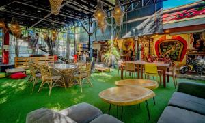 a room with a green floor and tables and chairs at Cafe Moto Hostel in Puerto Princesa City