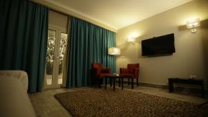 a hotel room with a television and red chairs at Kemzo Hotel in Abū Rawwāsh