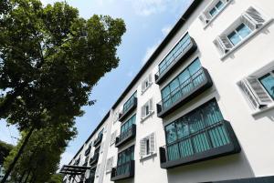 a white building with windows and a tree at Link Hotel Singapore in Singapore