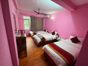 a room with three beds with pink walls at Om Tara Guest House Pvt Ltd in Kathmandu