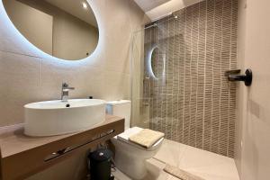 a bathroom with a sink and a toilet and a mirror at GLEN Premium Stays in Kanali +28 photos