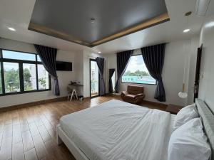 a bedroom with a bed and a chair and windows at AOC HOTEL in Cao Lãnh