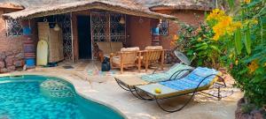 a pool with a chair and a table next to a house at Villa Les Flamboyants in Somone