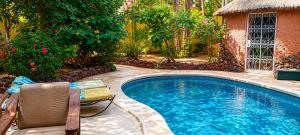 a swimming pool with a chair next to a house at Villa Les Flamboyants in Somone