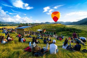 a crowd of people sitting in a field watching a hot air balloon at Zion Campsite in Ziro