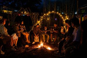 a group of people sitting around a fire at night at Zion Campsite in Ziro