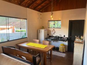 a kitchen with a wooden table and a refrigerator at Lar temporário Rê Auer in Santa Teresa