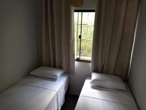 two beds in a small room with a window at Lar temporário Rê Auer in Santa Teresa