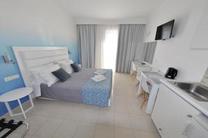 a bedroom with a bed and a kitchen with a sink at Golden View Studios in Lindos
