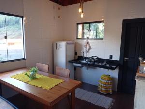 a kitchen with a wooden table and a refrigerator at Lar temporário Rê Auer in Santa Teresa +7 photos