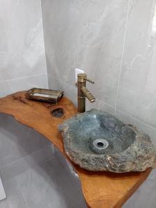 a bathroom with a stone sink on a wooden counter at Lar temporário Rê Auer in Santa Teresa