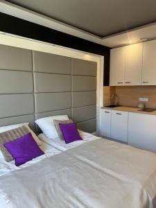 a bedroom with a large white bed with purple pillows at Apartament Piano 21 in Opole +4 photos