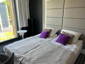 a bedroom with a white bed with purple pillows at Apartament Piano 21 in Opole