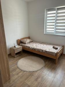a bed in a room with a window and a rug at Apartman Šarenac in Bileća