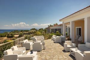 a patio with white chairs and a view of the ocean at Porto Skala Village Hotel in Skala