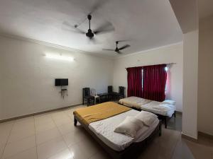 a bedroom with two beds and a table with a tv at Manipal Downtown in Manipal