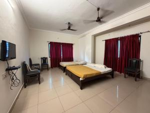 a bedroom with two beds and a flat screen tv at Manipal Downtown in Manipal