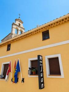 a yellow building with flags on the side of it at Hostal Don Juan in Alarcón