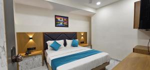 a bedroom with a large bed with blue pillows at Hotel Sunrise in Ahmedabad +8 photos