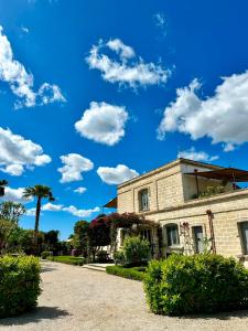 a brick building with a blue sky with clouds at Casina Metrano - Castello Monaci in San Pancrazio Salentino