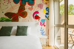 a bedroom with a white bed with flowers on the wall at Green Hôtels Bordeaux Arena in Latresne +50 photos