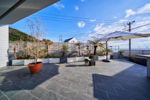 a patio with an umbrella and potted plants at The Blue House in Katsuura