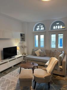 a living room with a couch and a tv at Sea views - Marble Palace - 2 floors in Tinos