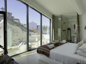 a bedroom with a bed and large glass windows at Casa Matriz Séc. XVI | Double or Twin w/ balcony in Penafiel