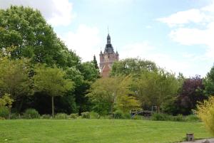 a building with a clock tower in the middle of a park at La Courée d'Orchies in Loos