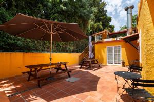 a picnic table with an umbrella on a patio at Penedo Escape Nature in Colares