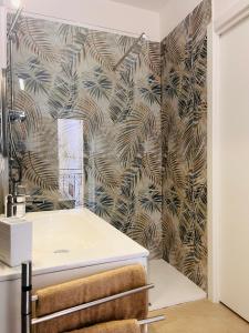 a bathroom with a white sink and a palm tree wallpaper at 'Na Scalunera in Mezzojuso +25 photos
