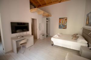 a white living room with a bed and a tv at OASI Apartment in Le Grazie