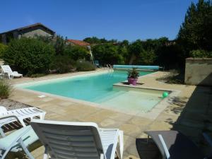 a swimming pool with chairs and a ball in it at Gîtes Du Logis De Bourseguin in Bourneau