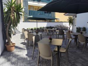 ein Restaurant mit Tischen, Stühlen und Sonnenschirmen in der Unterkunft Hotel Costa Azzurra in Grado