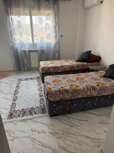 a bedroom with two beds and a tiled floor at Apparemment f3 délit Ibrahim in Deli Ibrahim