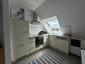 a kitchen with white cabinets and a window at Gemütliche Maisonette nahe Dinkelsbühl in Schopfloch +23 photos