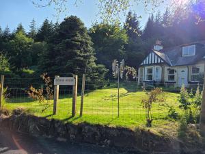 a sign in the grass in front of a house at Doune House Pods in Beauly
