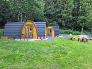a small yellow and blue house in a yard at Doune House Pods in Beauly