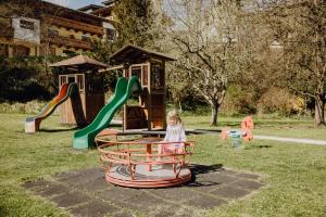 a little girl sitting on a playground ride at Hotel Dorfcafe Unken in Unken