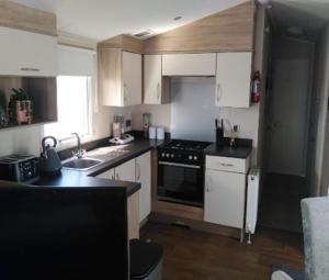 a kitchen with white cabinets and a stove top oven at Lymington in Leysdown-on-Sea