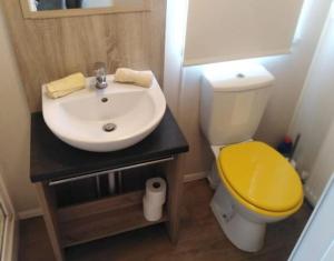a bathroom with a yellow toilet and a sink at Lymington in Leysdown-on-Sea