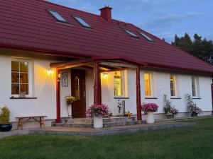 ein weißes Haus mit einem roten Dach und einer Bank in der Unterkunft Folwark Miodobytek in Łomnica