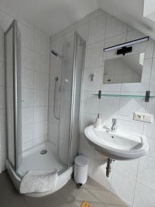 a white bathroom with a shower and a sink at Gemütliche Maisonette nahe Dinkelsbühl in Schopfloch